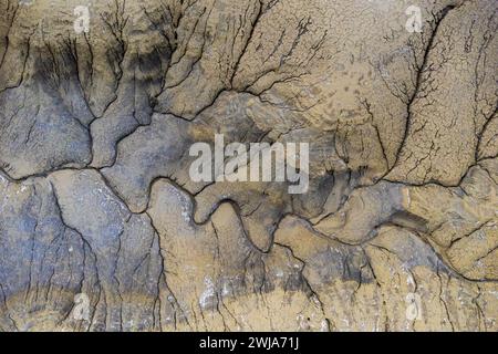 Aerial image of a dried riverbed with deep erosion patterns and cracks in the desert of Utah, showcasing dramatic earth textures Stock Photo