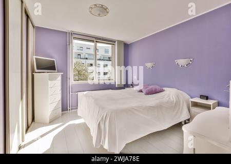 A bright and inviting lavender bedroom with modern decor and a view of the city Stock Photo