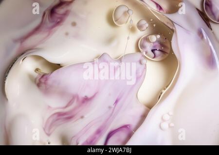 Delicate swirls of purple and white ink intertwined with tiny bubbles against a creamy background, creating a dreamy abstract pattern Stock Photo