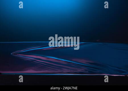 An abstract image featuring flowing liquid waves set against a gradient blue background, creating a serene and artistic visual Stock Photo