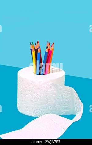 Colored pencils arranged in a roll of white toilet paper against a blue background Stock Photo