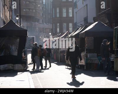 View of the street food section of Leather Lane Market in the Holborn area of the City of London, UK. The market, operating primarily during weekday lunchtimes, features a diverse array of stalls selling international street food, fresh produce, flowers, fashion, and homeware Stock Photo