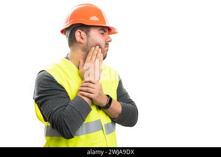 Male construction trades industry worker wearing uniform fluorescent vest and helmet  having toothache touching cheek with blank copyspace isolated on Stock Photo