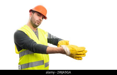 Serious constructor man getting ready for trades industry work wearing safety equipment orange hardhat and vest putting yellow gloves on isolated on w Stock Photo