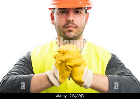Close-up of serious adult builder man wearing yellow work gloves fluorescent vest and safety helmet as industry work attire concept isolated on white Stock Photo