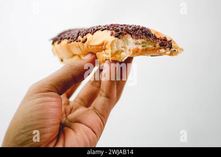 Close up hand holding bread with chocolate sprinkles topping meses isolated on white background Stock Photo