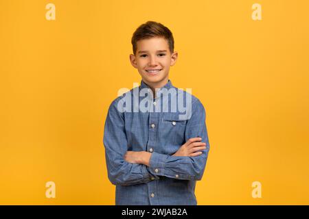 Confident teen boy in blue denim shirt standing with arms crossed Stock Photo