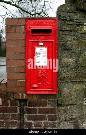 Kearsley Manchester January 2024, Royal mail square red post box in the stone and brick wall with collection times printed on white notice plate UK Stock Photo