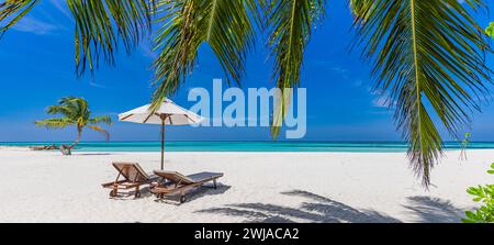 Amazing beach. Romantic chairs umbrella panoramic sandy beach palm leaves, sun sea sky. Summer holiday couples vacation. Love happy tropical landscape Stock Photo