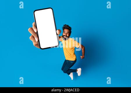 Energetic middle aged indian man jumping with phone in hand Stock Photo