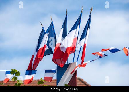 French blue, white and red flags in “place de la mairie” (Townhall Square) on the occasion of the National Day of July 14th in Saint-Pierre-de-Varenge Stock Photo
