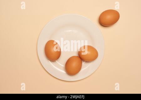 Eggs on a white plate, from above, on a buff coloured background Stock Photo