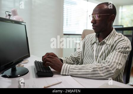 Portrait of serious Black software developer reviewing programming code on computer screen Stock Photo