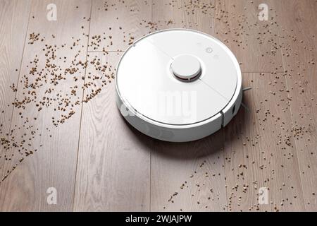 Smart robot vacuum cleaner removes scattered debris from the laminate floor. The concept of a smart home, wireless cleaning of any surfaces Stock Photo