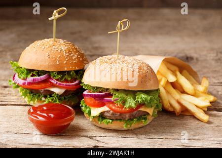 Two hamburgers, french fries and sauces on a rustic wooden background. Fast food, homemade burgers Stock Photo