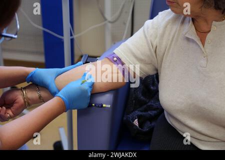 Nurse Inserting a Cannula into Patient Ready to Administer Ferinject Iron Infusion Intravenously At Hospital Surrey England Stock Photo