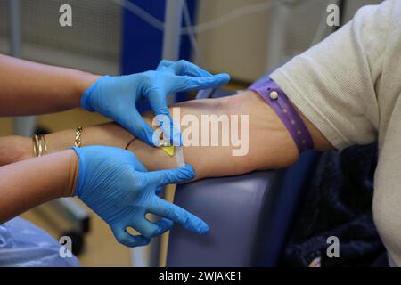 Nurse Inserting a Cannula into Patient Ready to Administer Ferinject Iron Infusion Intravenously At Hospital Surrey England Stock Photo