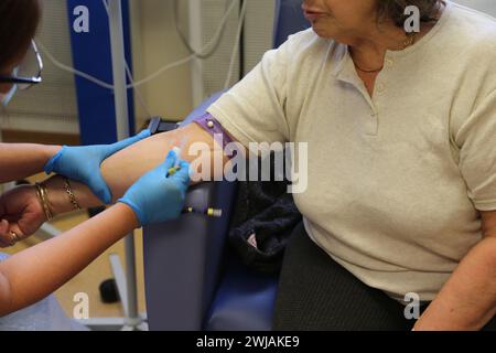 Nurse Inserting a Cannula into Patient Ready to Administer Ferinject Iron Infusion Intravenously At Hospital Surrey England Stock Photo