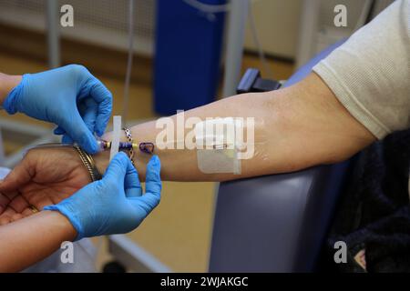 Nurse Inserting a Cannula into Patient Ready to Administer Ferinject Iron Infusion Intravenously At Hospital Surrey England Stock Photo