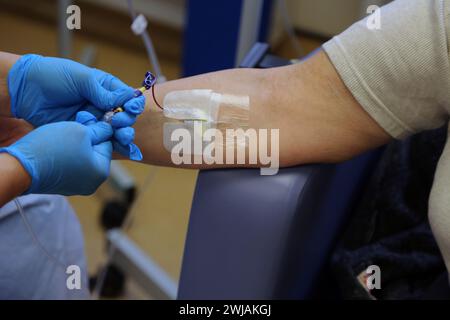 Nurse Inserting a Cannula into Patient Ready to Administer Ferinject Iron Infusion Intravenously At Hospital Surrey England Stock Photo