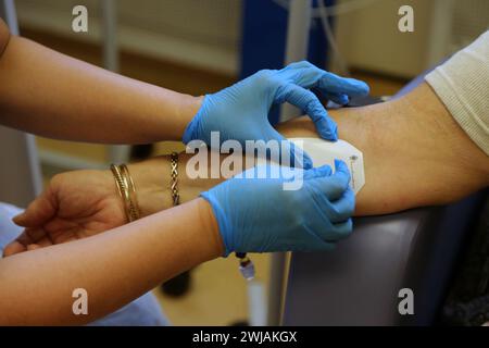 Nurse Inserting a Cannula into Patient Ready to Administer Ferinject Iron Infusion Intravenously At Hospital Surrey England Stock Photo