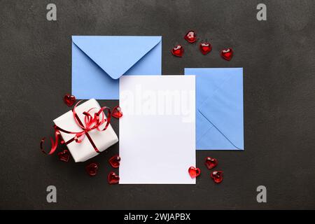 Envelopes with blank card, gift box and hearts on black grunge background. Valentine's Day celebration Stock Photo