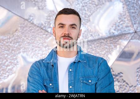 portrait young caucasian serious man with arms crossed outdoors. Stock Photo