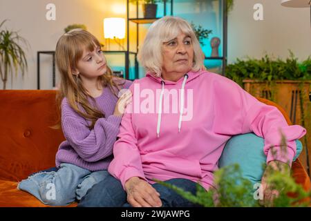 Loving worried kind girl granddaughter consoling sad crying grandmother helping with problem comforting talking to upset senior woman in tears, empathy support embracing sitting on sofa in living room Stock Photo