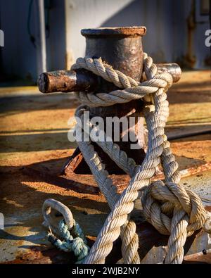 Closeup of a tie up line on a boat and the rusty cleat that it is tied to. Stock Photo