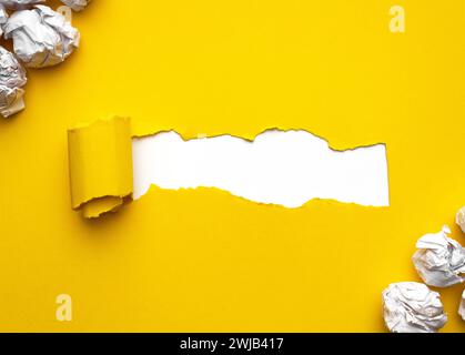 Yellow torn Paper with white crumpled paper balls on white background. Space for text. Stock Photo