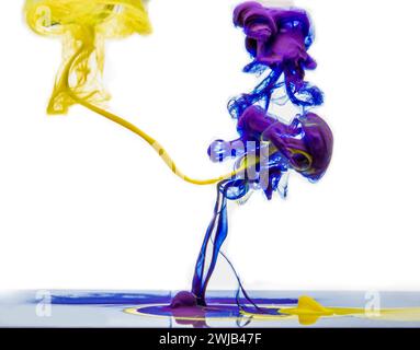 Colors dropped into liquid and photographed while in motion on white background. Color drop. Selective focus. Stock Photo