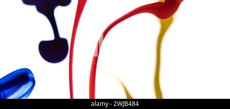 Colors dropped into liquid and photographed while in motion on white background. Color drop. Selective focus. Stock Photo