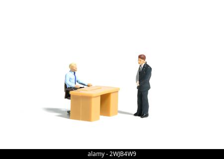 Miniature tiny people toy figure photography. Office coaching and briefing illustration concept. A staff employee facing boss. Image photo Stock Photo