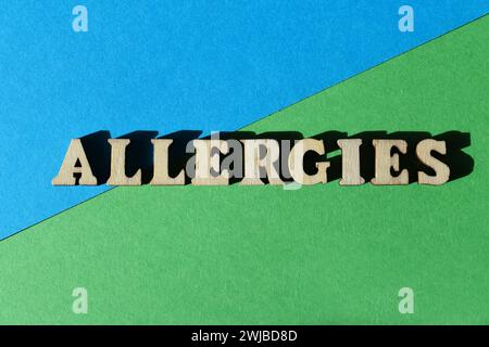 Allergies, word in wooden alphabet letters isolated on green and blue background as banner headline Stock Photo