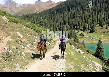 August 31 2023 - Semyonovka, Kyrchyn Valley in Kyrgyzstan: People riding horses in north of Kyrgyzstan mountains Stock Photo