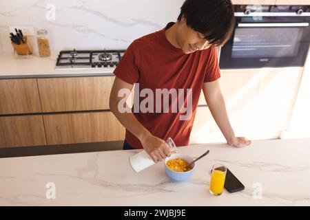 Teenage Asian boy prepares breakfast in a modern home kitchen Stock Photo