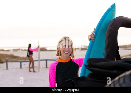 Young Caucasian woman smiles holding a surfboard Stock Photo