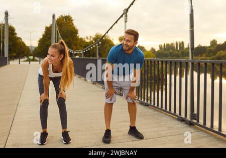 Young energetic sports couple who are training together taking break from exercising outdoors. Stock Photo