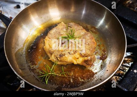 A piece of lamb leg is fried in oil in an iron pan. Stock Photo
