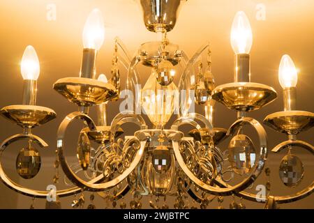 crystal chandelier with glowing light bulbs hanging from the ceiling in the room Stock Photo