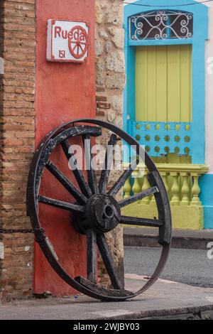 Old wagon wheel. Architectural detail in the old Colonial City of Santo Domingo, Dominican Republic.  A UNESCO World Heritage Site in the Dominican Re Stock Photo