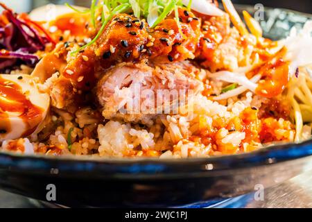 Spicy sweet and sour asian bowl with chicken, shrimp, seed,egg and vegetable in blue bowl, closeup. Stock Photo
