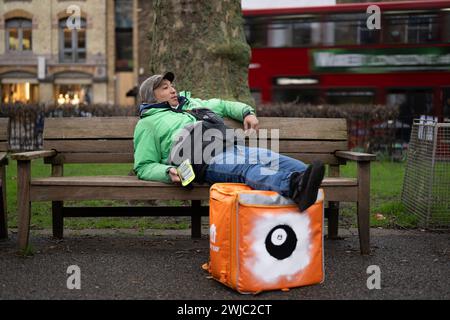 14th February 2024: An Uber Eats food courier takes a break between jobs in Islington Green, London. Deliveroo, and Uber Eats couriers are striking tonight between five and ten o’clock to secure better working conditions and pay. Stock Photo