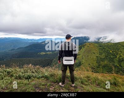 A hiker, having taken off his backpack, looks around to determine the route Stock Photo