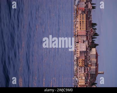 View of the embankment of Rovinj from the sea. The ships are in the harbor and the sunset sky is reflected in the ripples on the waves on the surface Stock Photo