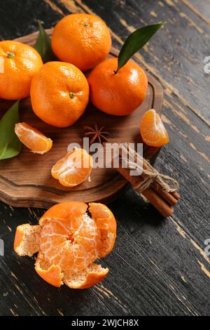 Board of sweet mandarins with cinnamon and star anise on black wooden background Stock Photo