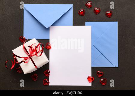 Envelopes with blank card, gift box and hearts on black grunge background. Valentine's Day celebration Stock Photo