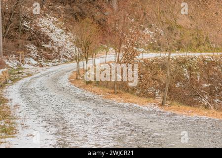 Gravel one lane road on side on mountain with snow on ground on sunny winter day Stock Photo