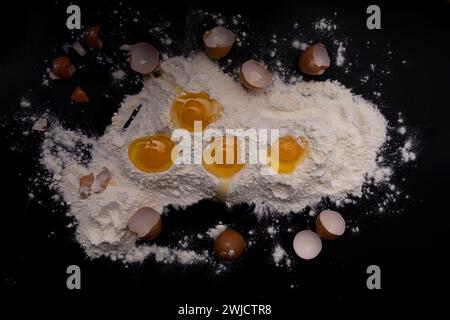 flour and broken chicken eggs on a black background. Stock Photo