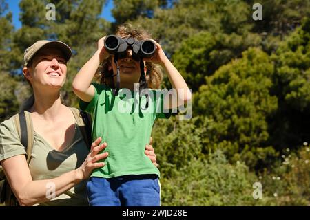 Mother and son using binoculars in nature Stock Photo